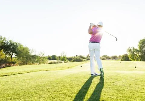 Hispanic golfer teeing off on golf course Photos