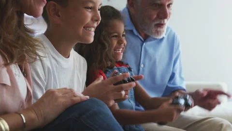 Hispanic Grandparents With Grandchildren Playing Video Game At Home Sitting On Stock Footage
