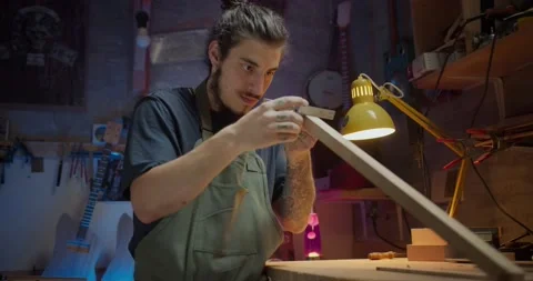 Hispanic guitar maker checking shape of wood plank concentrated at workshop Stock Footage 137241563