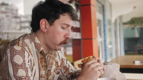 Hispanic guy eating burger. Junk food, modern life concept. Stock Footage 263806522