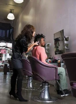 Hispanic hair stylist styling African woman's hair Stock Photos