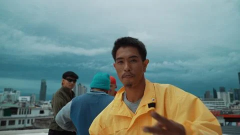 Hispanic hipster looking at camera surrounded by friend at rooftop. Hiphop. Stock Photos