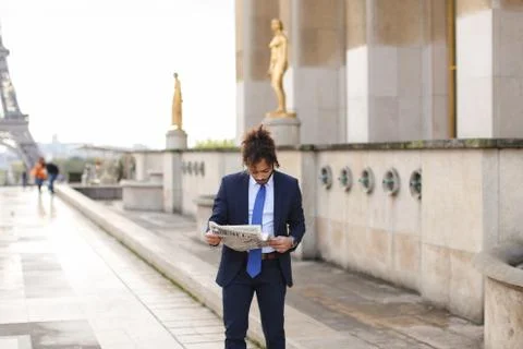 Hispanic journalist close to Eiffel Tower reading newspaper and Foto stock