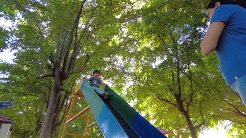 Hispanic kid playing in a playground on a slide very happy with his mother Stock-Footage 264230973