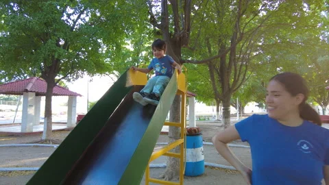 Hispanic kid playing in a playground on a slide very happy with his mother Stock-Footage 264232785