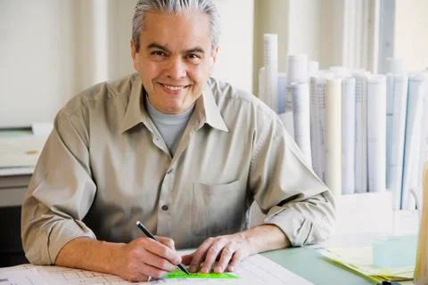 Hispanic male architect writing at desk Stock Photos