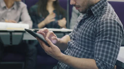 Hispanic male student is using a tablet computer in a college classroom Stock Footage 61164809
