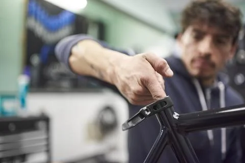 Hispanic man assembling a bicycle in his bike shop during maintenance service Stock Photos