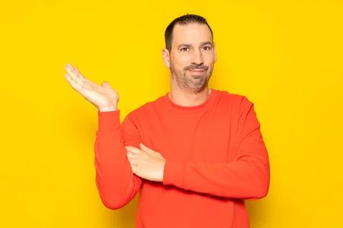 Hispanic man with a beard and red sweater in a friendly attitude offering som Stock Photos