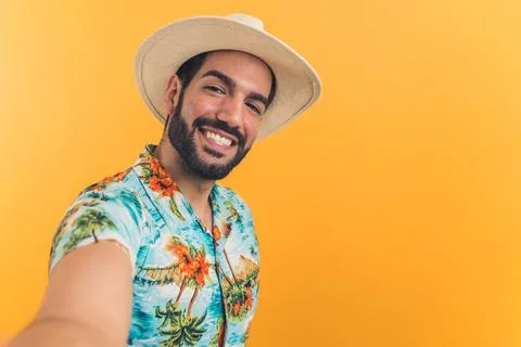 Hispanic man with beard wearing straw hat and summer clothes extending arm Stock Photos