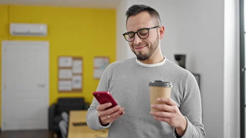 Hispanic man business worker using smartphone drinking coffee at office Stock Footage 246143464