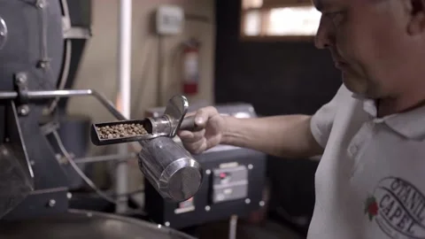An Hispanic man is checking beans roast from the coffee roaster machine Stock Footage 219592604