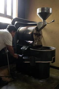 An Hispanic man is checking the burner of a coffee roaster machine Stock Photos