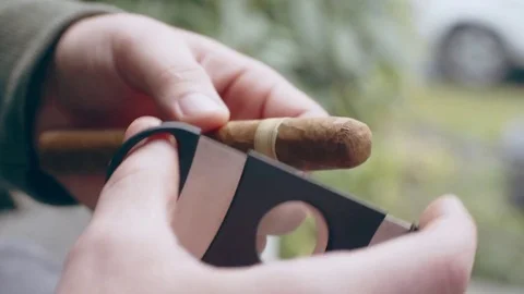 Hispanic man cutting end off fine cigar on front porch Stock Footage 84488488