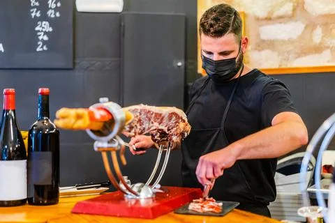 Hispanic man cutting meat on jamonera in wine bar Stock Photos