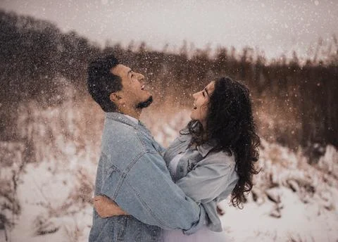 Hispanic man in denim jacket oversized and woman in love are kissing hugging  Stock Photos