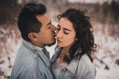 Hispanic man in denim jacket oversized and woman in love are kissing hugging  Stock Photos