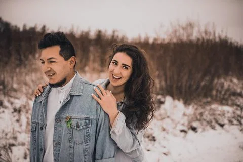 Hispanic man in denim jacket oversized and woman in love are kissing hugging  Stock Photos