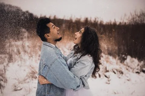 Hispanic man in denim jacket oversized and woman in love are kissing hugging  Stock Photos