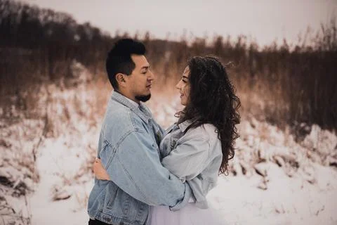 Hispanic man in denim jacket oversized and woman in love are kissing hugging  Foto stock