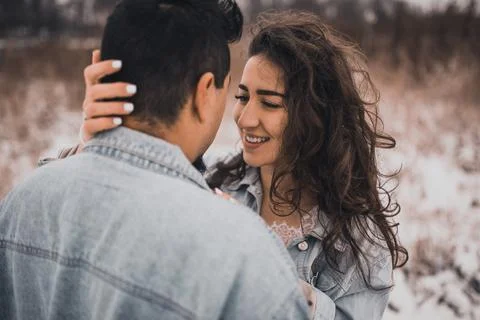 Hispanic man in denim jacket oversized and woman in love are kissing hugging  Stock-Fotos