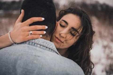 Hispanic man in denim jacket oversized and woman in love are kissing hugging  Stock Photos