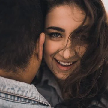 Hispanic man in denim jacket oversized and woman in love are kissing hugging  Stock Photos