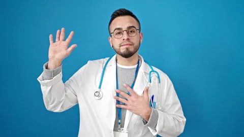 Hispanic man doctor making an oath with hand on chest over isolated blue ba.. Video stock 247384269
