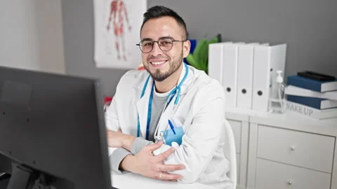 Hispanic man doctor using computer working at the clinic Video stock 246142998