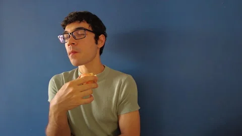 Hispanic man eating an apple on a blue background Video stock 240165589