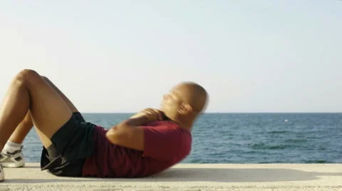 Hispanic man exercising abs near the sea Stock Footage 5030532