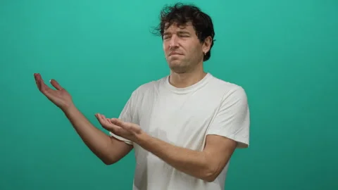 Hispanic man extends arms sideways against a vibrant green background expre.. Vidéo 306848714