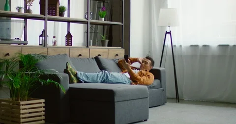 Hispanic man has a video chat, lying on sofa Vídeo Stock 115930201