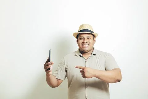 Hispanic man with hat pointing to the mobile very happy, on white background Stock Photos