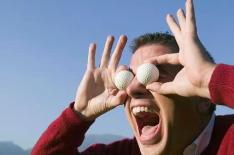 Hispanic man holding golf balls over eyes Stock Photos