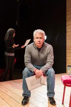 Hispanic man holding script on theater stage Stock Photos