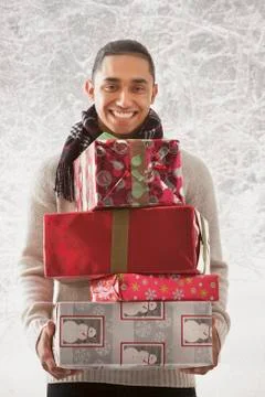 Hispanic man holding stack of presents in snow Stock Photos