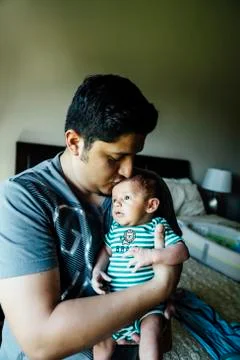 Hispanic man kissing forehead of baby boy Stock Photos