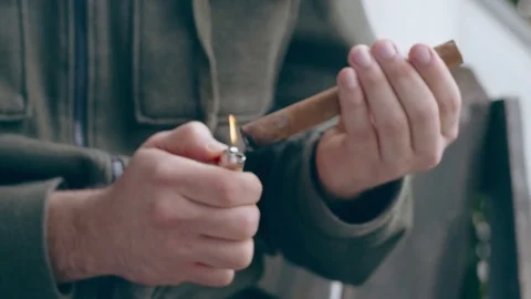 Hispanic man lighting end of fine cigar on front porch Stock Footage 84490701