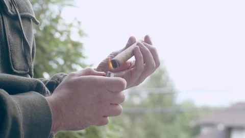 Hispanic man lighting end of fine cigar on front porch Stock Footage 84491096