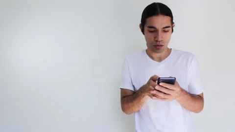 Hispanic man with long hair using a smart phone on a white background Video stock 192482519