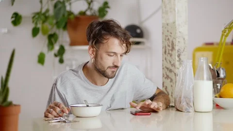 Hispanic man looking at display of smartphone enjoying morning flake meal with Stock Footage 108796068