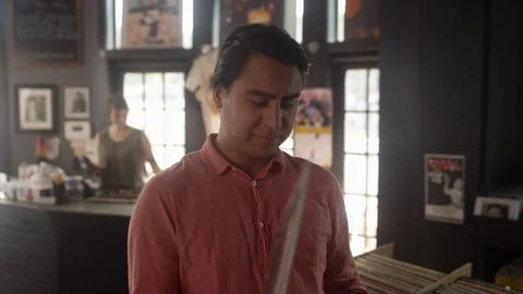 Hispanic man looking at a stack of vinyl records in a record store Stock Footage 122591639