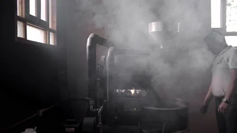 An Hispanic man is operating a coffee roaster machine surrounded by steam Stock Footage 219592864