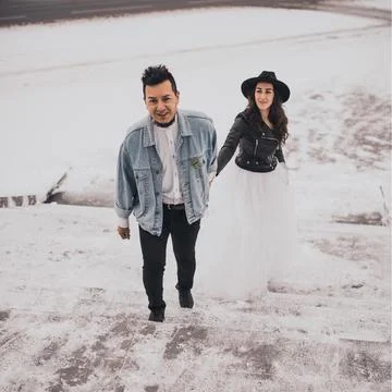 Hispanic man in oversized denim jacket and woman in hat leather biker jacket Stock Photos