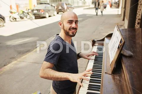 Hispanic Man Playing Piano On City Sidewalk