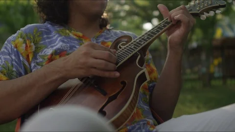 A hispanic man plays the mandolin in the backyard on a hot summer afternoon Video stock 125728661