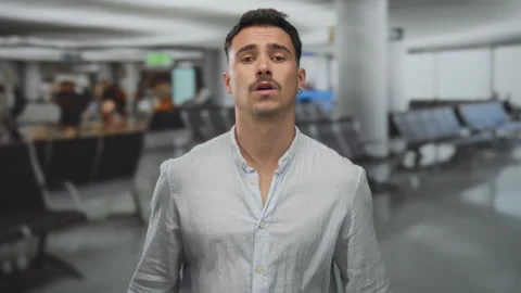 Hispanic man pleading inside busy airport with blurred background conveying.. Видео 314627367