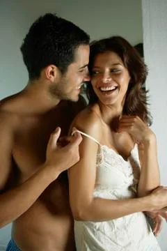 Hispanic man pulling down girlfriend's camisole strap Stock Photos
