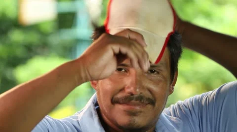 Hispanic man puts on cap smiles to camera. Close up Video stock 45525314